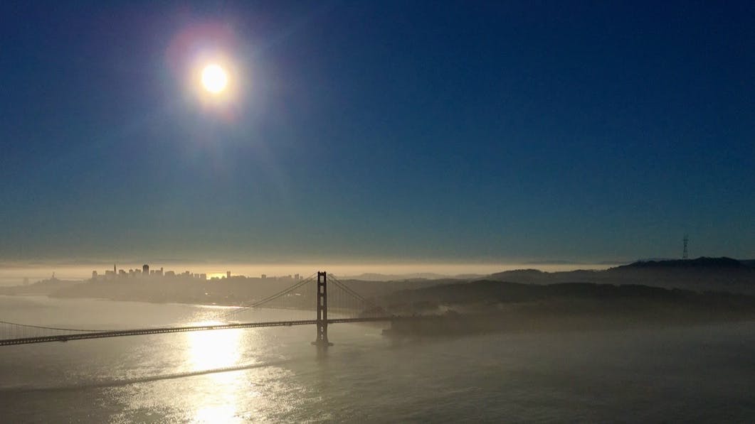 The sun shines over the Golden Gate Bridge and the city of San Francisco